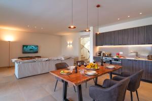 a kitchen and living room with a wooden table and chairs at Aethrion Villas & Suites in Gennadi +36 photos