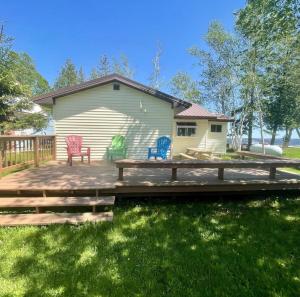 a deck with two chairs and a house at Cozy Cottage on Indian Lake with AC in Manistique