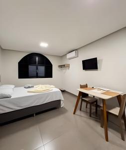 a bedroom with a bed and a table and a tv at Menezes Flat in Rio Verde