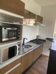 a small kitchen with a microwave and a sink at Residencial Luce Del Sole in Joinville