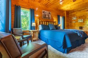 a bedroom with a bed and chairs in a log cabin at Bear Essentials Lodge By Avada Properties in Sevierville