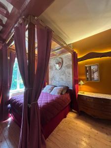 a bedroom with a canopy bed and a window at La Cage aux Oiseaux in La Lande-de-Goult