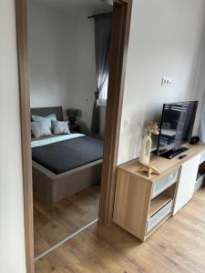 a mirror reflection of a bedroom with a bed and a television at Lily Beach Apartman in Balatonlelle