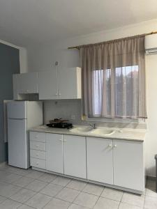a kitchen with white cabinets and a window at Blue Sky Apartments 3 in Hanioti