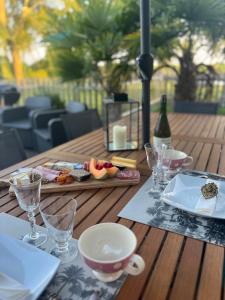 a wooden table with a tray of food and wine glasses at SUITES EN PERCHE-Proche Mortagne in Bures