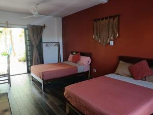 two beds in a room with red walls and a window at Secret paradise mahahual in Mahahual