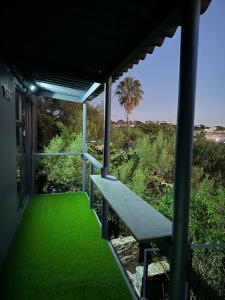 a porch with green grass and a bench at The Bachelor in Mossel Bay