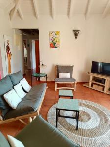 a living room with a couch and a tv at Villa Les Bougainvilliers in Capesterre-de-Marie-Galante