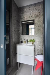 ein Badezimmer mit einem weißen Waschbecken und einem Spiegel in der Unterkunft La Maison du Traict Chambres d'hôtes in Le Croisic