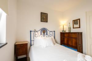 a bedroom with a white bed and a wooden dresser at Casa do Pisco - by Smarthomes in São Martinho do Porto