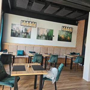 a restaurant with wooden tables and green chairs at Apartament Sikorskiego 27 in Ełk
