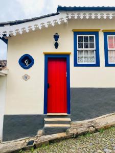 a red door on a white house at Cantinho Pilar in Ouro Preto