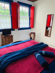 a bedroom with a bed with red and blue sheets at Cantinho Pilar in Ouro Preto