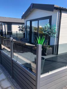a deck with glass doors and a potted plant at Bliss on the Bay at Waterside Holiday Park in Paignton