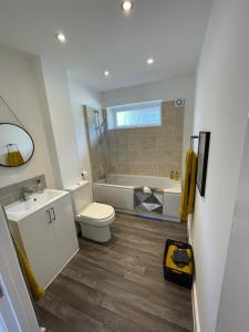 a bathroom with a toilet and a tub and a sink at Quiet and Central, Modern Bungalow in Hereford
