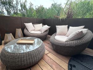 two wicker chairs and a table on a deck at Le Cocon de Sophie in Bénodet +2 photos