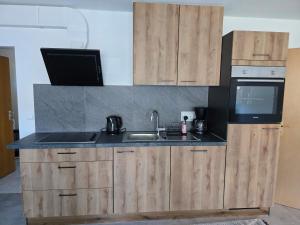 a kitchen with wooden cabinets and a sink and a microwave at Ferienwohnung Baj in Albstadt