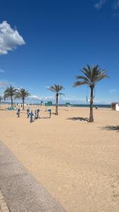 a beach with palm trees and people sitting on benches at Tikitita House in Gandía
