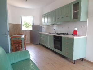 a kitchen with green cabinets and a stove top oven at Capomare2 in Capo Vaticano +37 photos