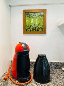 eine orange-schwarze Kaffeemaschine und eine Vase auf einer Theke in der Unterkunft Cantinho Familia in Ouro Preto