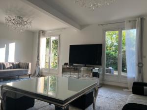 a living room with a table and a tv at Maison Serenity Domont Retreat in Domont