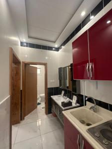 a kitchen with two sinks and a red cabinet at منازل الباحة للشقق الفندقية in Al ‘Āmirah +26 photos