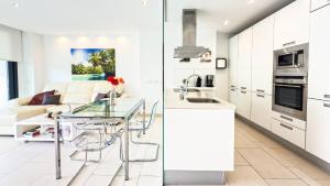 eine Küche mit weißen Schränken, einem Tisch und einer Couch in der Unterkunft Las Olas - Luxury apartment in Palm-Mar in Palm-mar + 55 Fotos