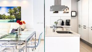 eine weiße Küche mit einem Glastisch und einem Waschbecken in der Unterkunft Las Olas - Luxury apartment in Palm-Mar in Palm-mar