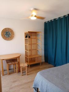 a bedroom with a bed and a table and a blue curtain at Front de mer - Le Barcarès in Le Barcarès