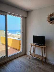 a room with a television on a table next to a window at Front de mer - Le Barcarès in Le Barcarès
