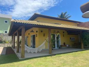 a yellow house with a hammock in front of it at Casa condominio Aldeiá de jacuipe in Barra de Jacuípe
