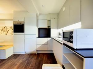 kuchnia z białymi szafkami i kuchenką mikrofalową w obiekcie Modern and comfortably furnished apartment w mieście Robertville