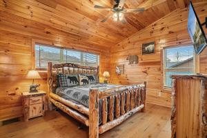 a log cabin bedroom with a bed and a ceiling fan at Hickory Haven By Avada Properties in Gatlinburg