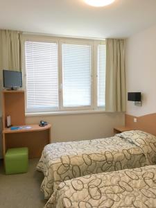 a hotel room with two beds and two windows at CEU Konferencia Központ in Budapest