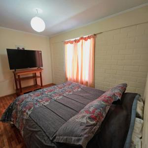 a bedroom with a bed and a flat screen tv at Cabaña Vicuña in Vicuña