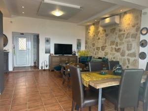 a living room with a table and chairs and a tv at Villa Evdokia II in Makry Gialos