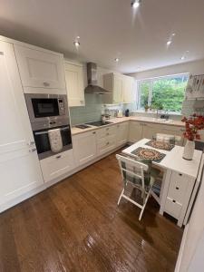 a kitchen with white cabinets and a table with a chair at Pippins in Tiverton