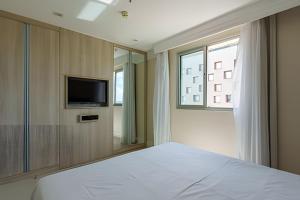 a bedroom with a bed and a tv and a window at Flat moderno Hotel Mercure Líder in Brasilia