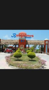 ein Schild für ein Geschäft mit zwei Bäumen und Blumen in der Unterkunft Bungalows village Town house T3 in Dawwār Abū Duray‘ah ‘Abd al Karīm