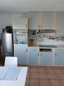 a kitchen with white cabinets and a stainless steel refrigerator at Ferienwohnung zum Flaaden in Neumünster