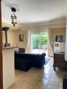 a living room with a black couch and a kitchen at le cachot de st Cricq in Cérons