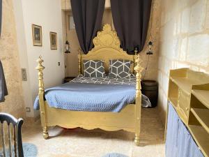a bedroom with a gold bed with a blue comforter at le cachot de st Cricq in Cérons +4 photos