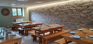 a dining room with wooden tables and a brick wall at La Marmotte De La Meije in Le Bourg-dʼOisans