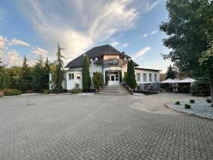 a large white building with a large driveway at Cliff House & Restaurant in Żary