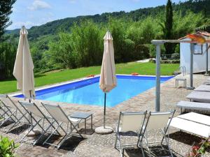 un gruppo di sedie e ombrelloni accanto alla piscina di Spacious Villa in Sermugnano with Swimming Pool a Castiglione in Teverina