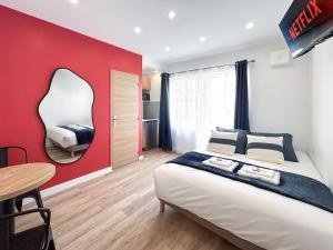 1 dormitorio con pared roja, cama y mesa en Villa des Camelias, en Le Pré-Saint-Gervais