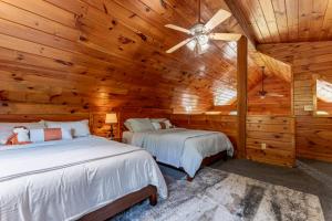2 bedden in een blokhutslaapkamer met een plafondventilator bij Fantastic Mr. Fox By Avada Properties in Pigeon Forge