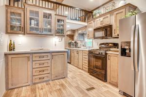 a kitchen with wooden cabinets and a stainless steel refrigerator at Walk to Lake Beaches Cabin with Patio in Belmont! in Belmont +22 photos