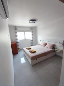 a white bedroom with a bed and a window at Casa Zenn in Puerto del Rosario