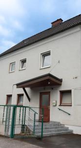 a white house with a fence in front of it at Zentrale Ferienwohnung mit kostenlosen Parkplätzen in Leoben